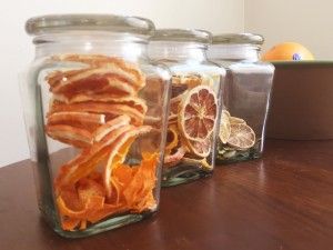 three glass jars filled with food sitting on top of a wooden table next to an orange