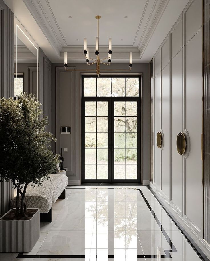 an elegant hallway with marble flooring and white walls, two planters on either side of the door