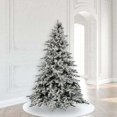 a white christmas tree sitting in the middle of a room next to a wall with an arched doorway