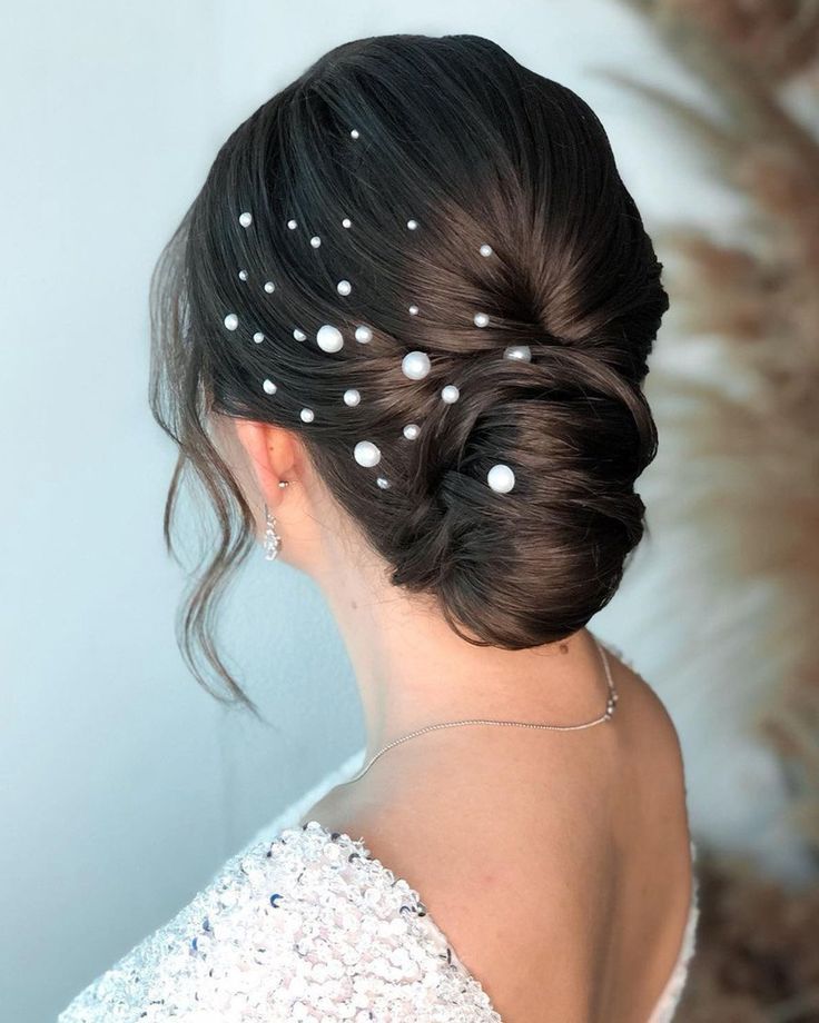 a woman in a white dress with pearls on her head and hair pinned into a low bun