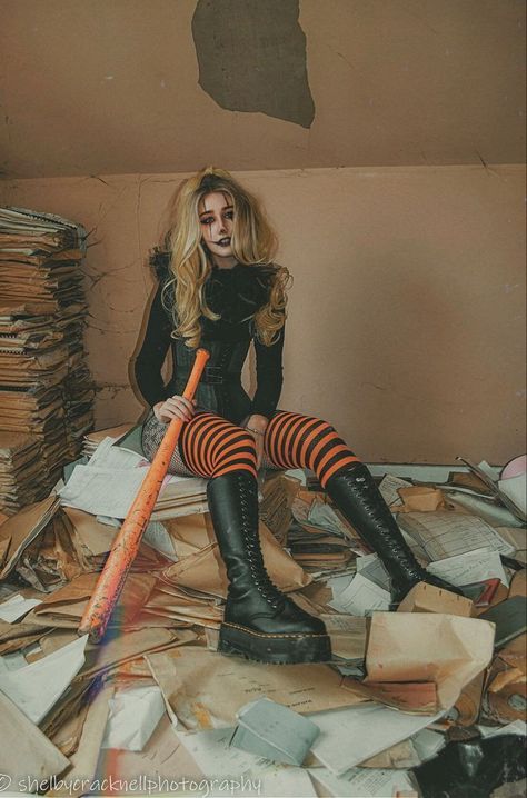 a woman sitting on top of a pile of papers with a bat in her hand