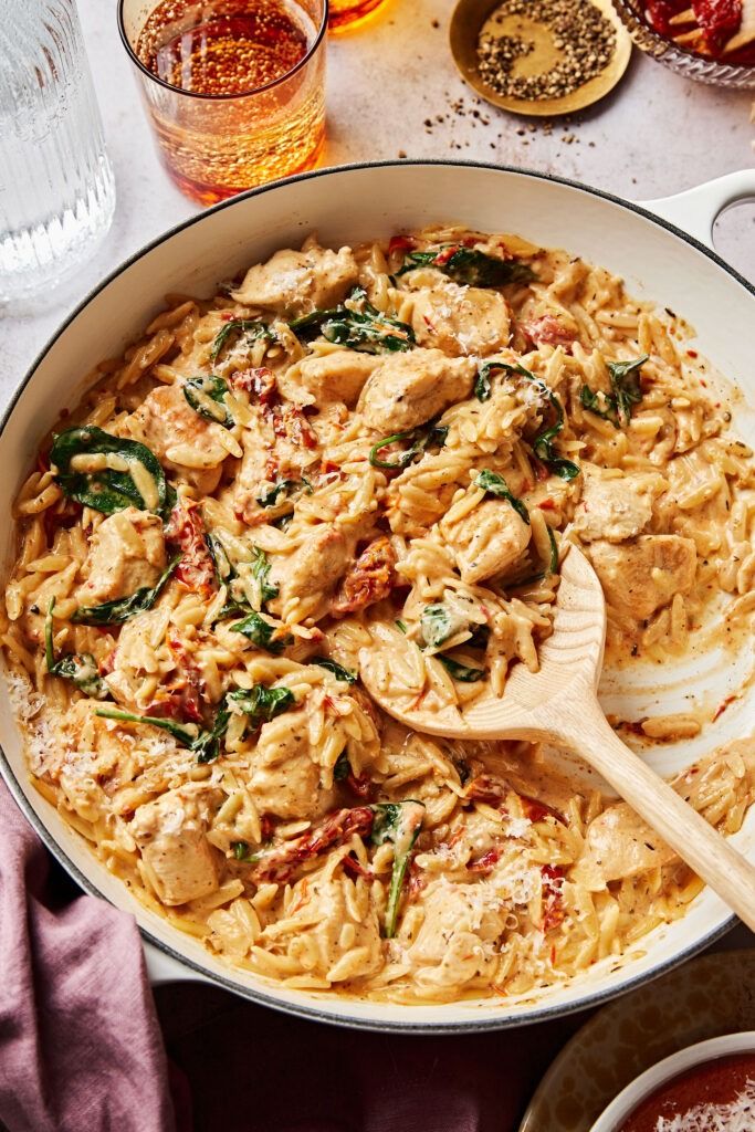 a pan filled with pasta and chicken on top of a table next to other dishes