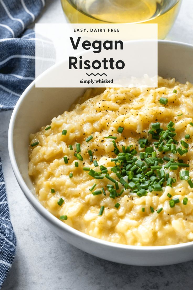 a white bowl filled with mashed potatoes and garnished with chives next to a glass of water