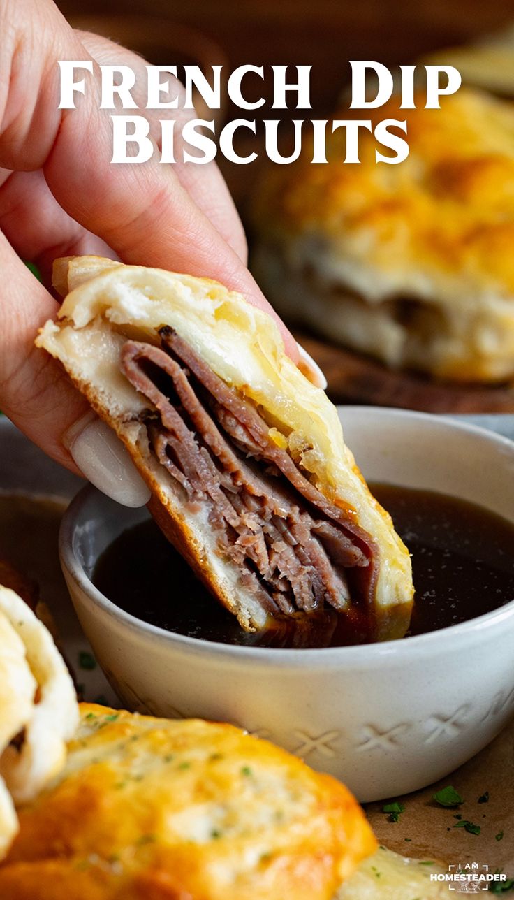 a person dipping some food into a small white bowl with black sauce in it and the words french dip biscuits above it