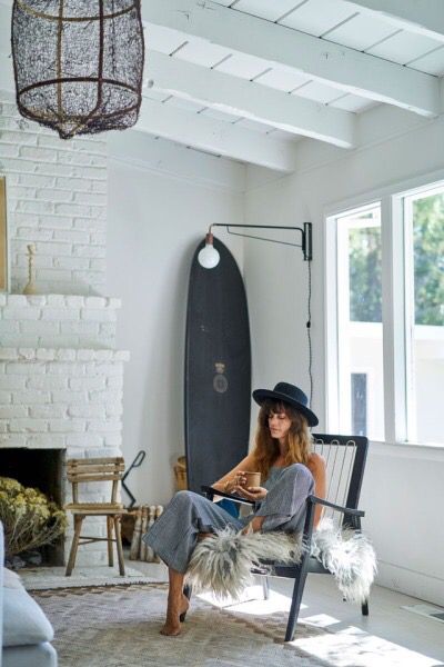 a woman sitting in a chair with a surfboard behind her and a lamp hanging from the ceiling