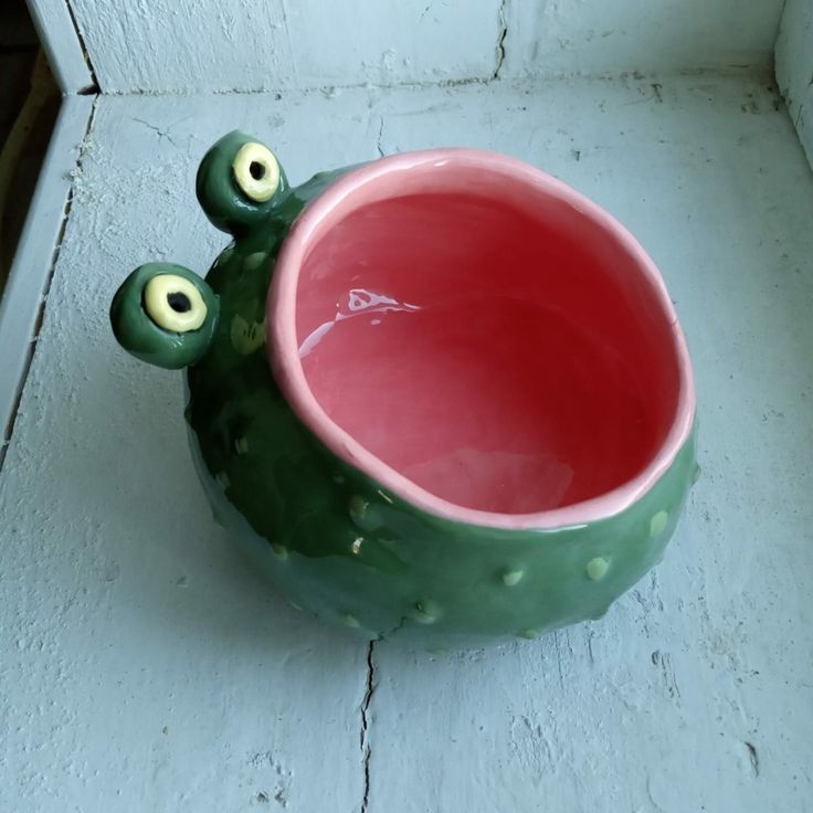 a green and pink cactus planter with googly eyes