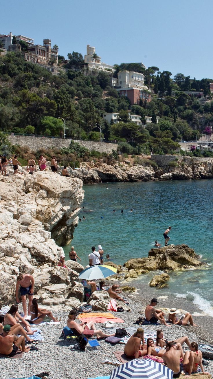 many people are relaxing on the beach by the water