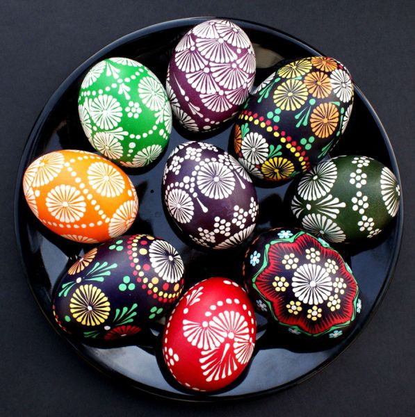 colorful painted eggs in a bowl on a black tablecloth with white and green designs