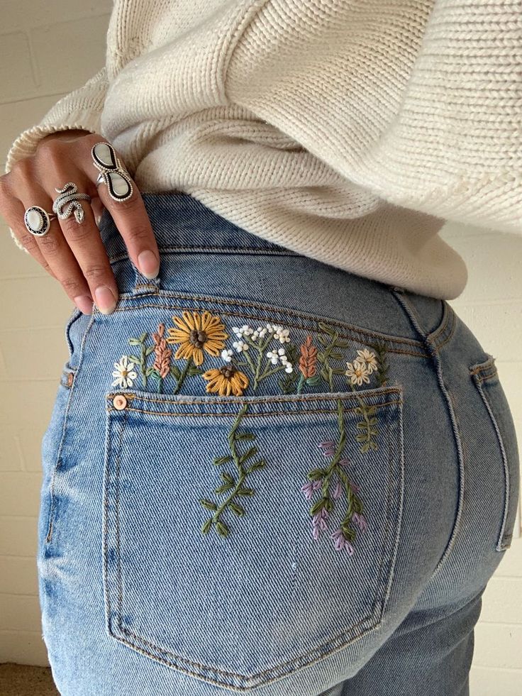 a woman wearing jeans with flowers painted on them