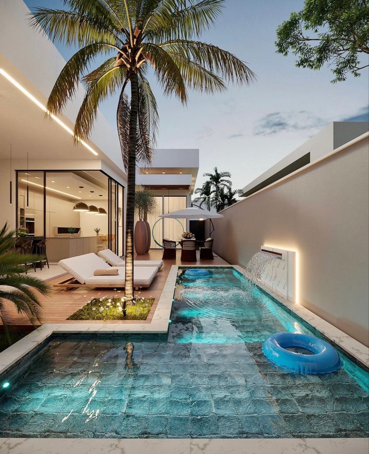 an indoor swimming pool with a palm tree and lounge chairs in the background at dusk