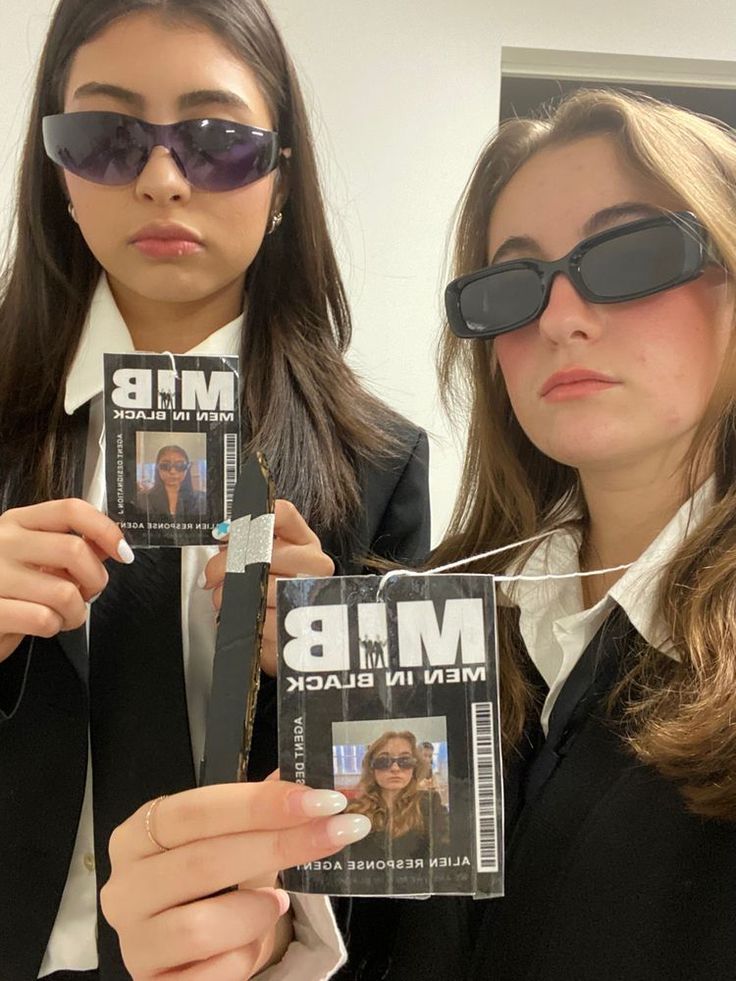 two women wearing sunglasses holding up magazines