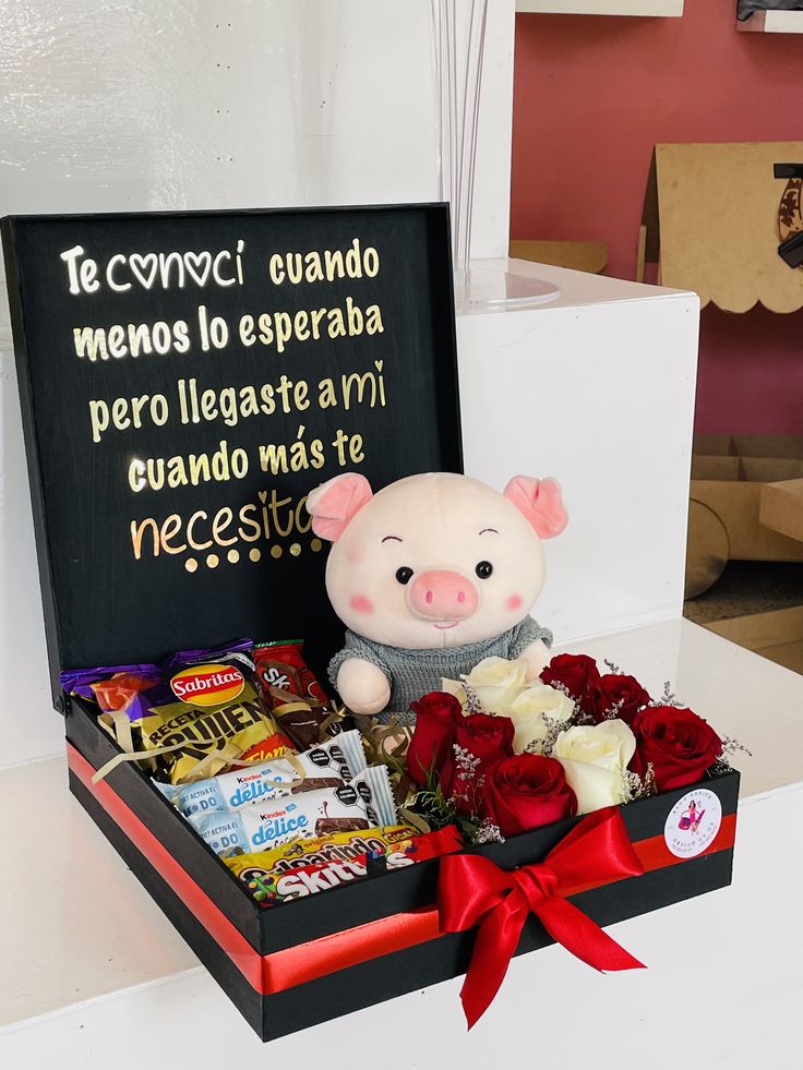 a stuffed pig in a gift box with roses and chocolates for someone to give