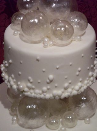 a three tiered white cake with bubbles on top