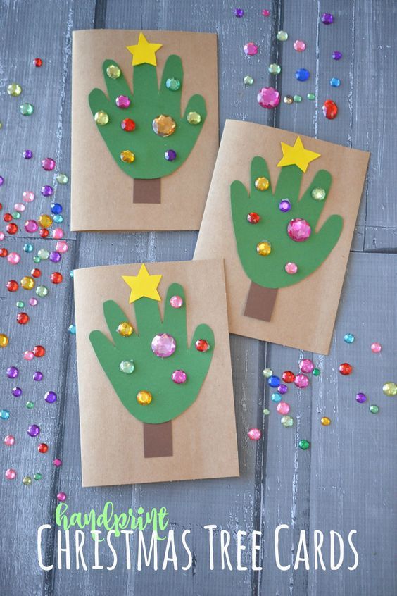 three handprinted christmas trees on brown paper with confetti scattered around them