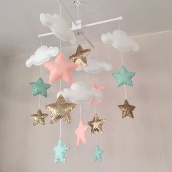 a baby mobile with stars and clouds hanging from it's sides in a room