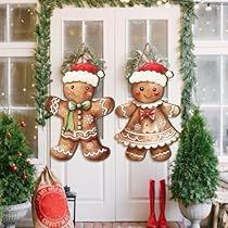 two gingerbread cookies are hanging on the front door with christmas decorations around them,