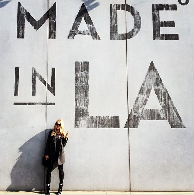 a woman standing in front of a wall that says made in la