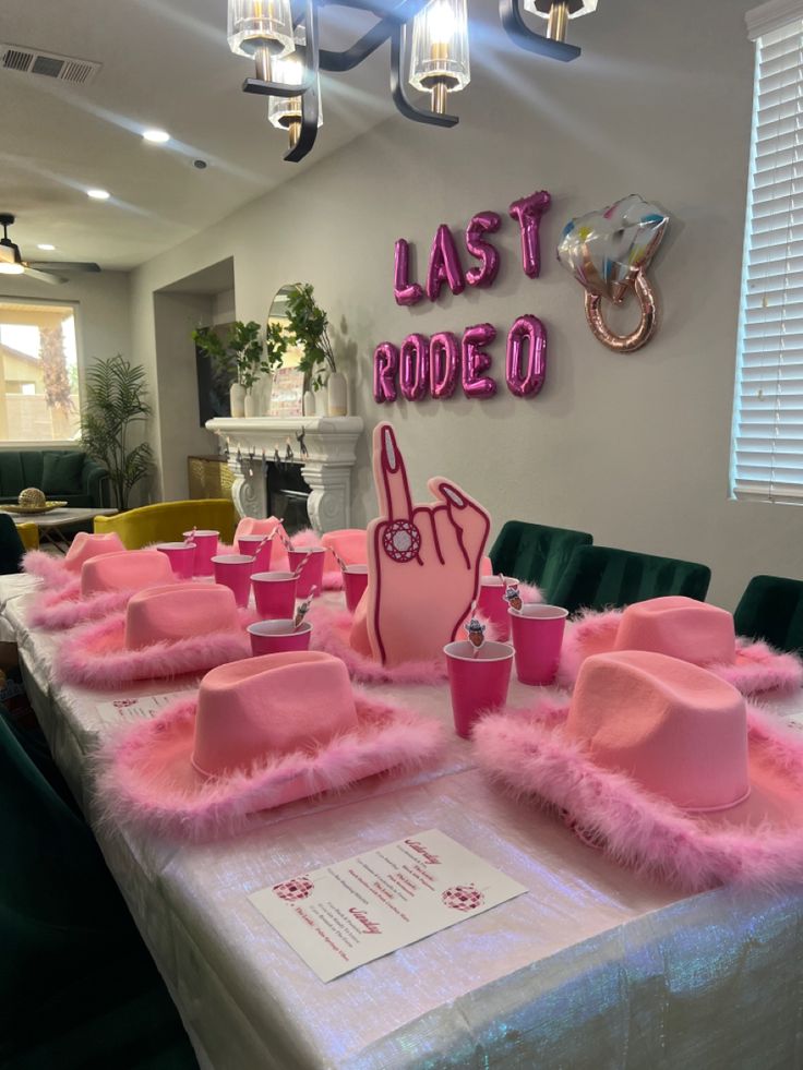 a table set up with pink hats and place settings for people to sit down at