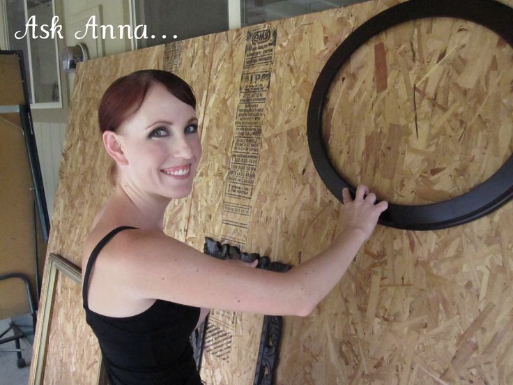 a woman is standing in front of a wooden wall with a circular object on it