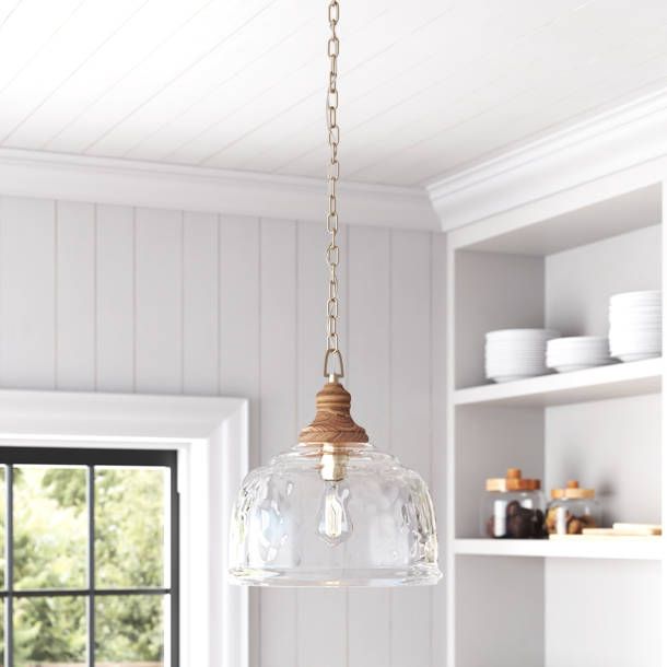 a light fixture hanging from the ceiling in a kitchen with white walls and wood floors