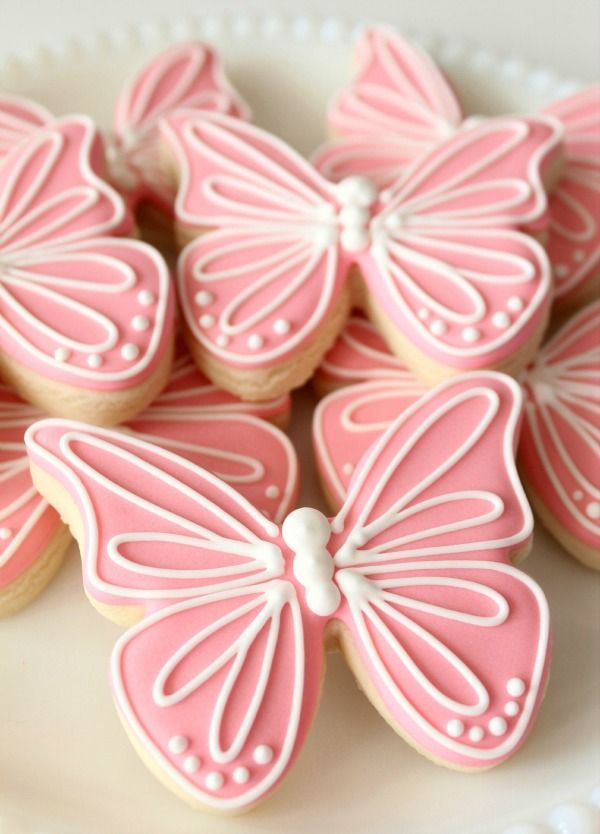 decorated cookies in pink and white are arranged on a platter with the words butterfly cut out