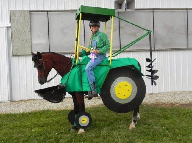 a man riding on the back of a horse with a tractor attached to it's side