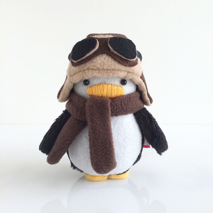 a stuffed penguin wearing a pilot's hat and scarf