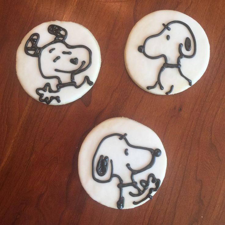 three decorated cookies with black and white frosting depicting snoopy the dog on them