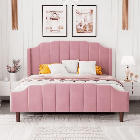 a pink bed with two framed pictures on the wall above it and a white rug in front of it