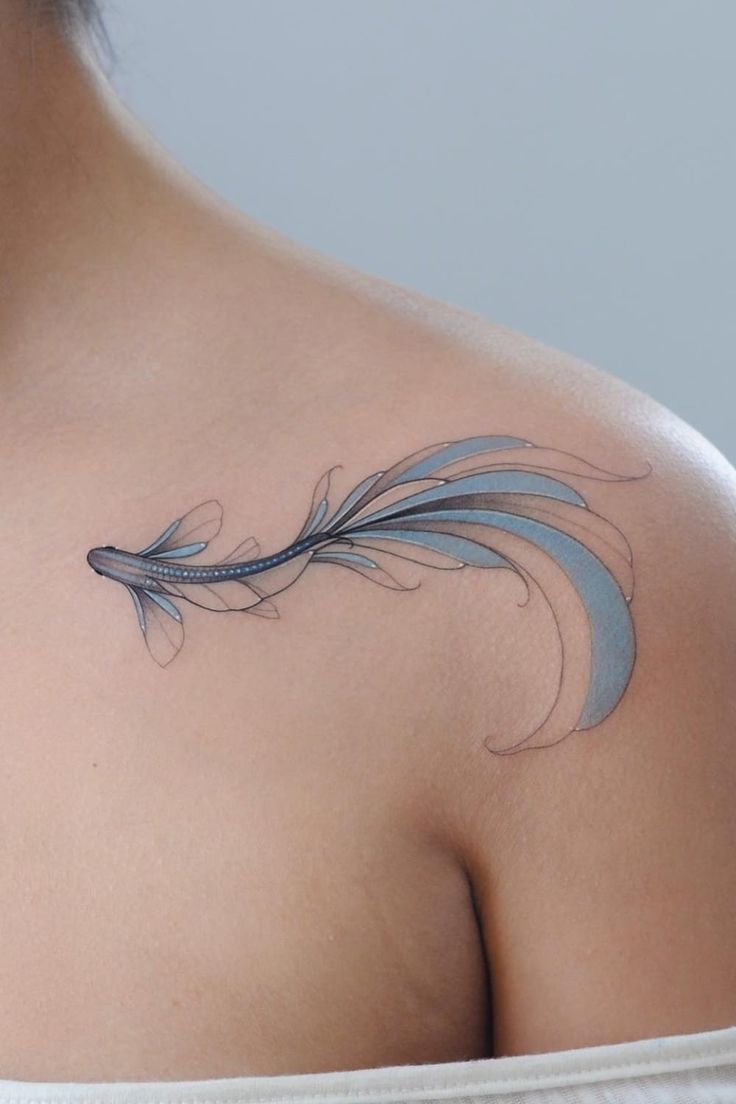 a woman with a tattoo on her shoulder has a blue feather in the shape of a heart