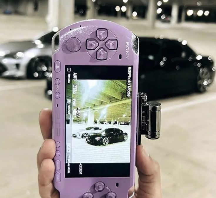 a person holding up a cell phone with a car on it's display screen