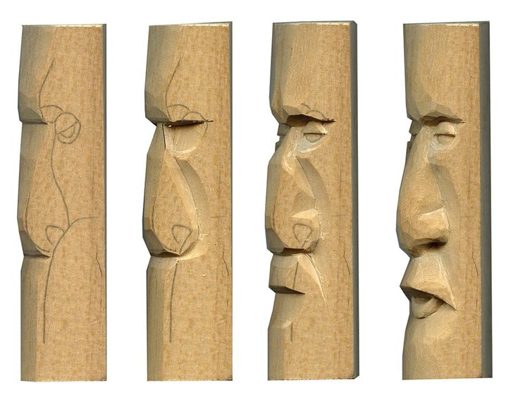 three carved wooden faces are lined up against each other