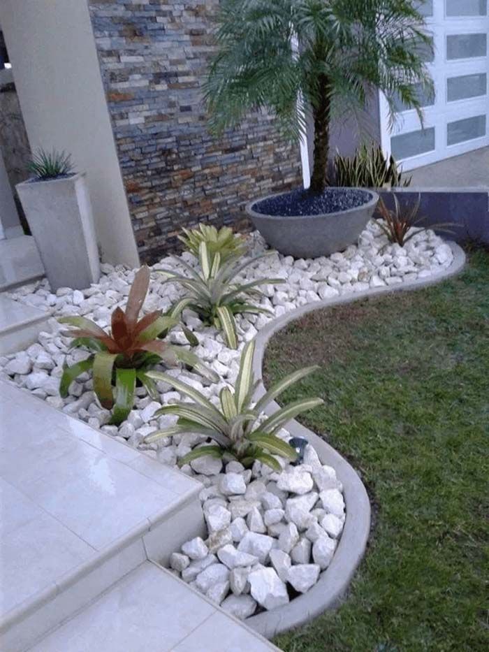 a small garden with rocks and plants in the front yard, next to a house