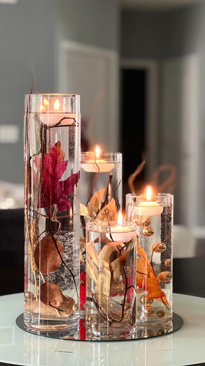 three glass vases filled with flowers and candles