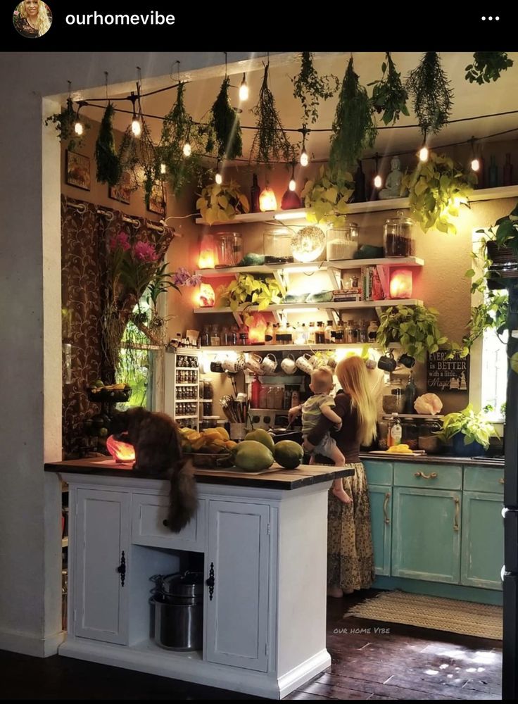 two women in a kitchen with plants hanging from the ceiling and potted plants on the shelves