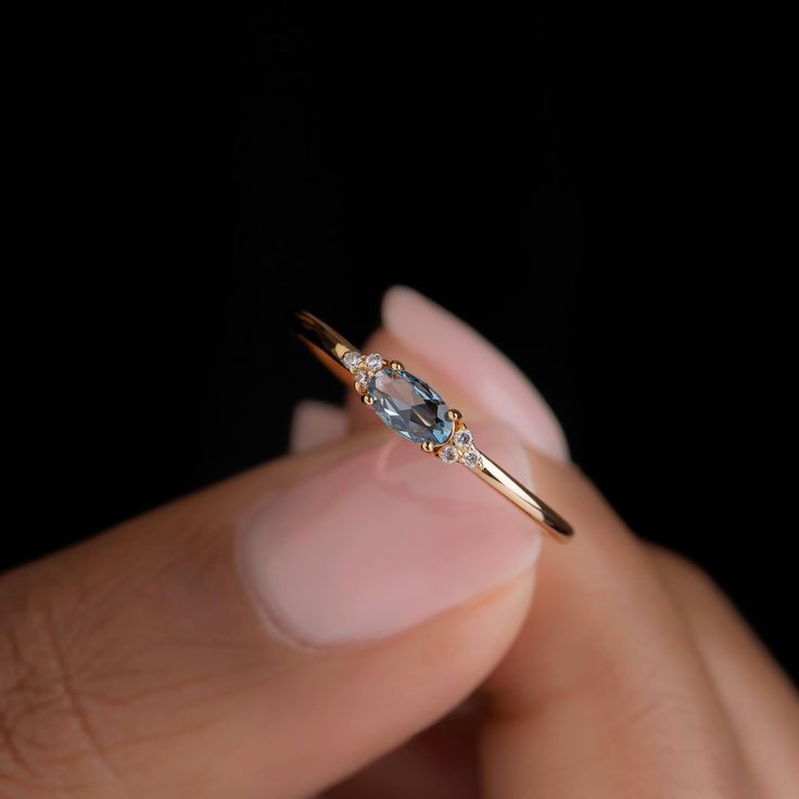 a woman's hand holding a ring with an oval shaped diamond on it and two small diamonds in the middle