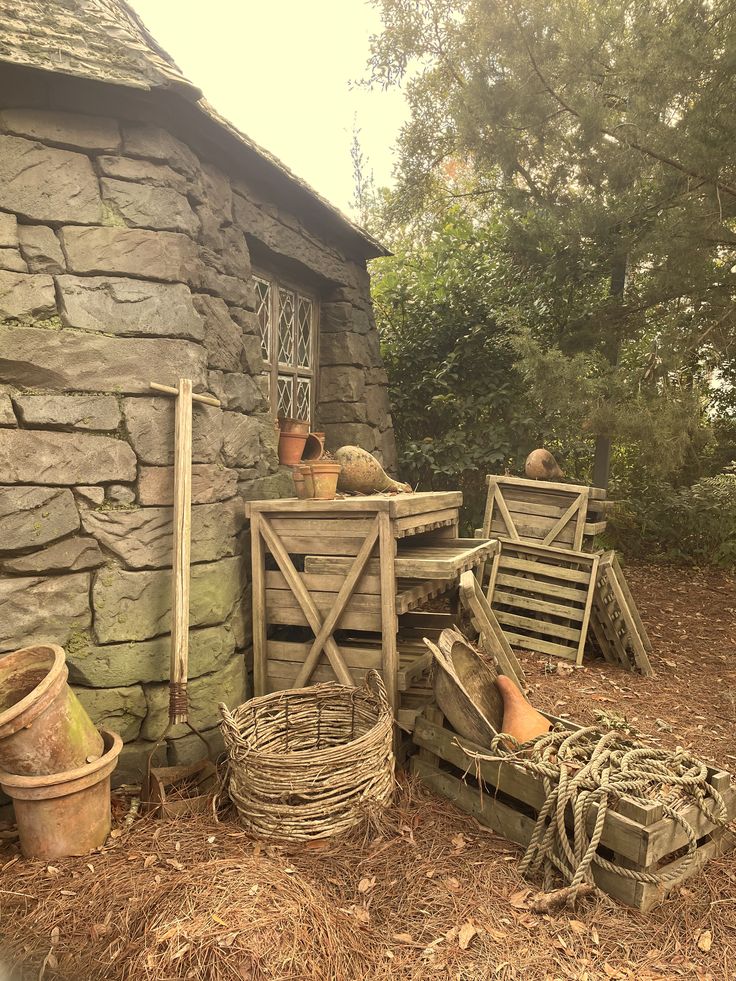 an old stone building with several wooden chairs and baskets on the ground next to it