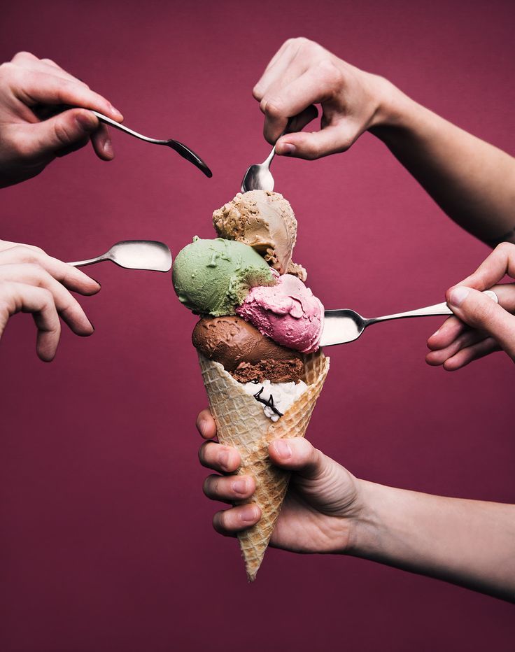 three people holding spoons and eating ice cream