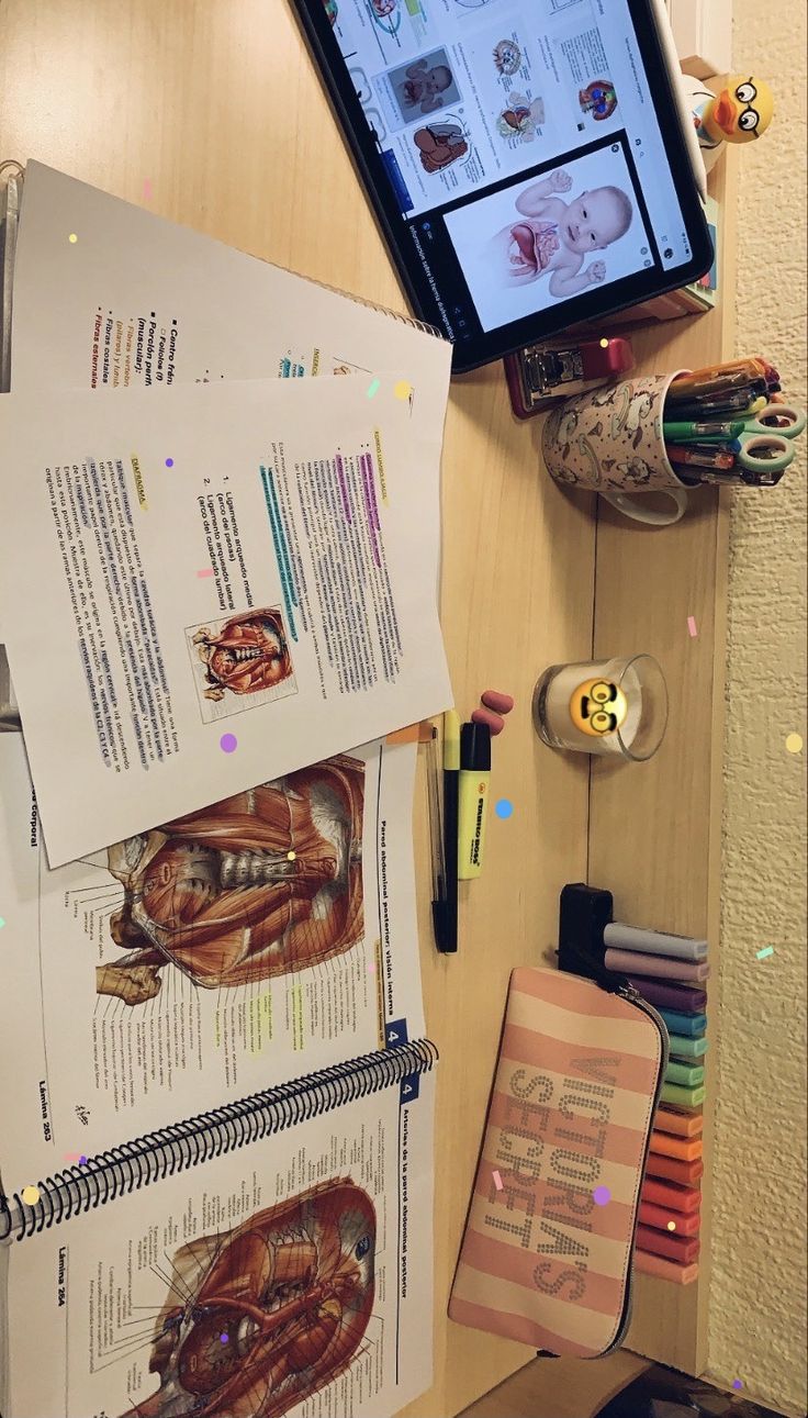 an open book sitting on top of a desk next to a computer monitor and pencils