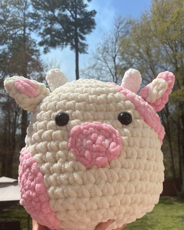 a crocheted stuffed animal that looks like a pig is held up to the camera