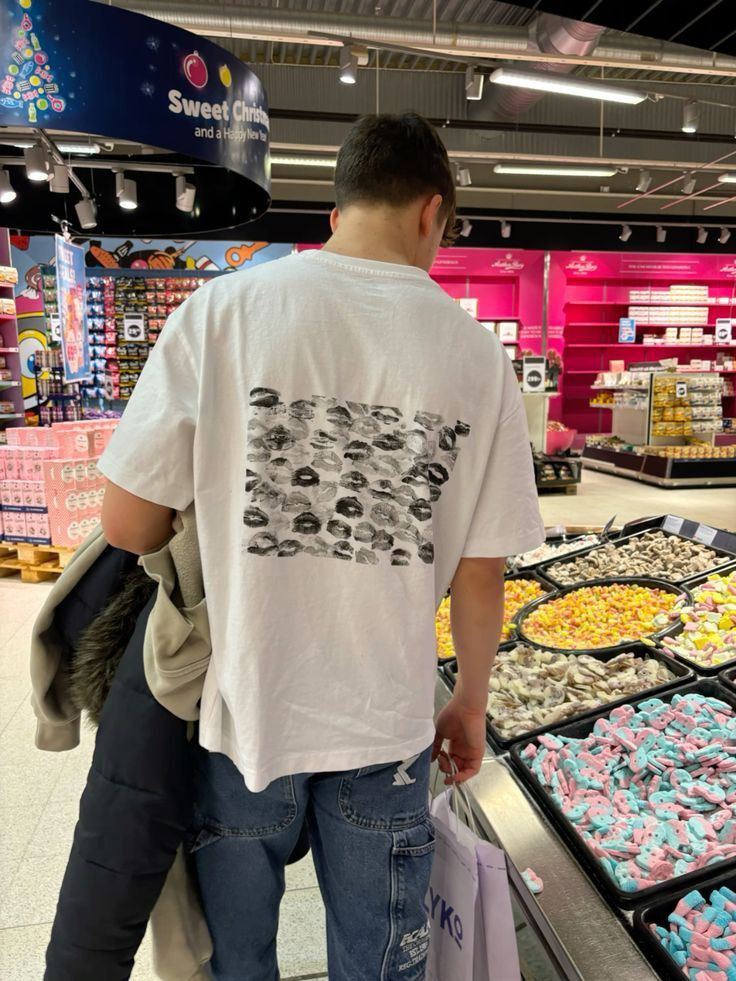 a man is shopping in a store with lots of donuts and other treats on display