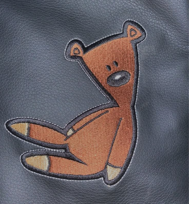 a teddy bear embroidered on the back of a leather jacket