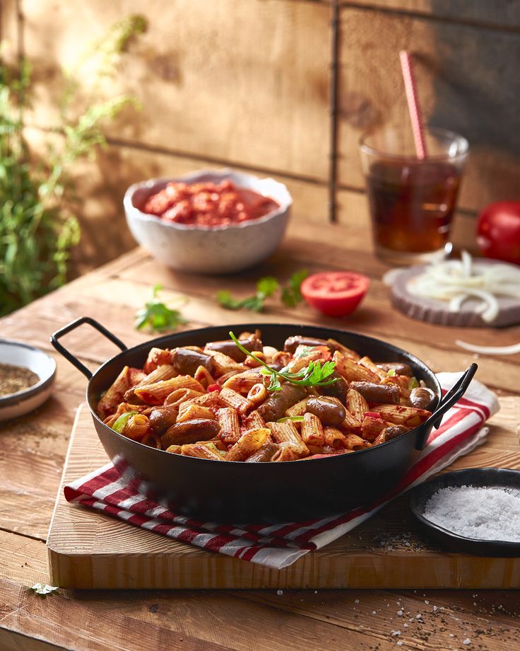 a pan filled with food sitting on top of a wooden table next to other dishes