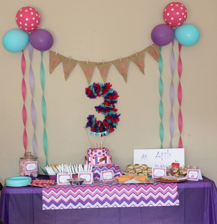 a purple table topped with cake and balloons