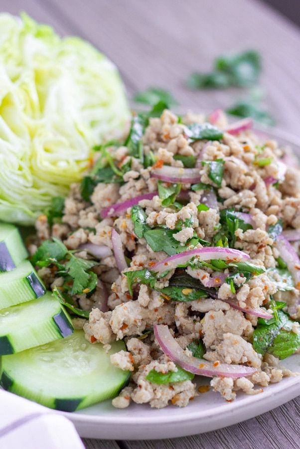 a white plate topped with meat and veggies on top of a wooden table