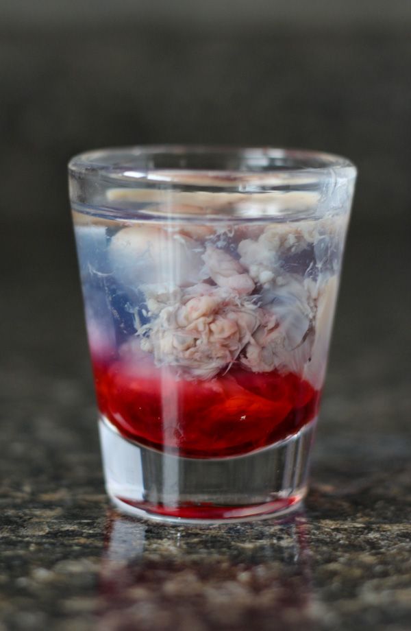 a shot glass filled with red liquid and flowers