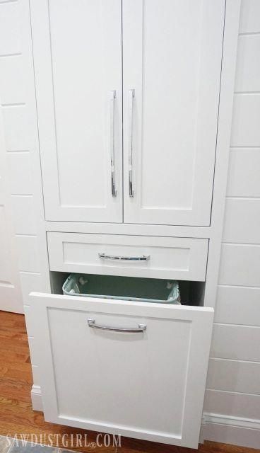 a white cabinet with two drawers in the middle and a door open to reveal an empty drawer