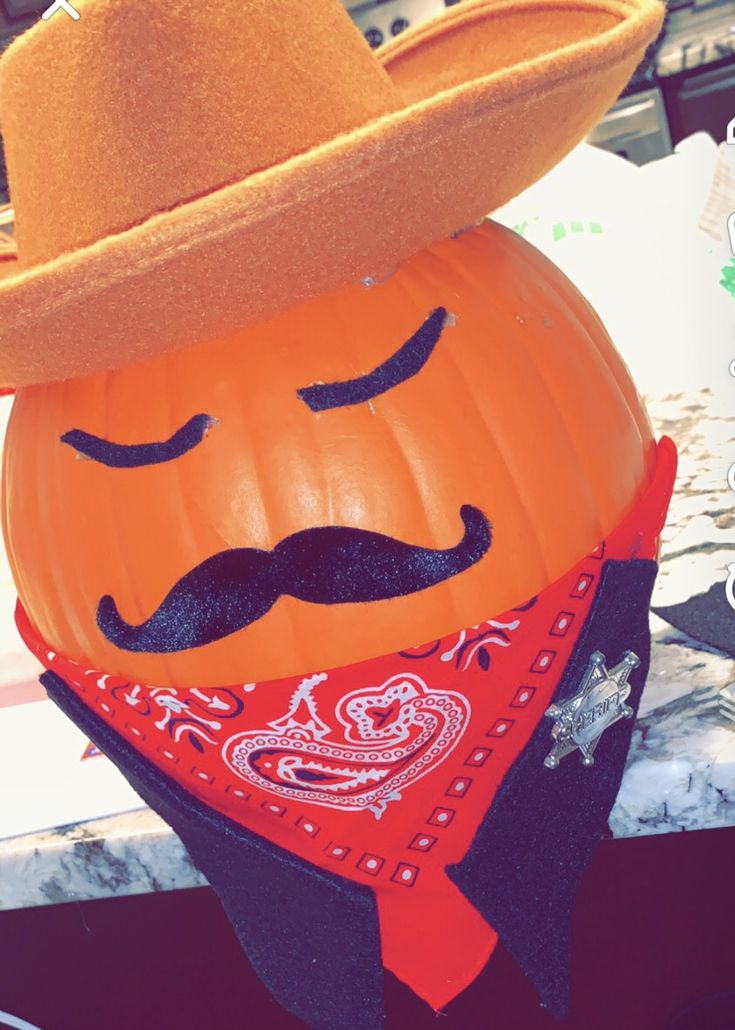 a pumpkin wearing a cowboy hat and bandana