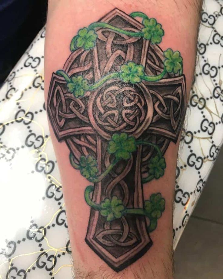 a cross with shamrocks on it is shown in this tattoo design by the artist