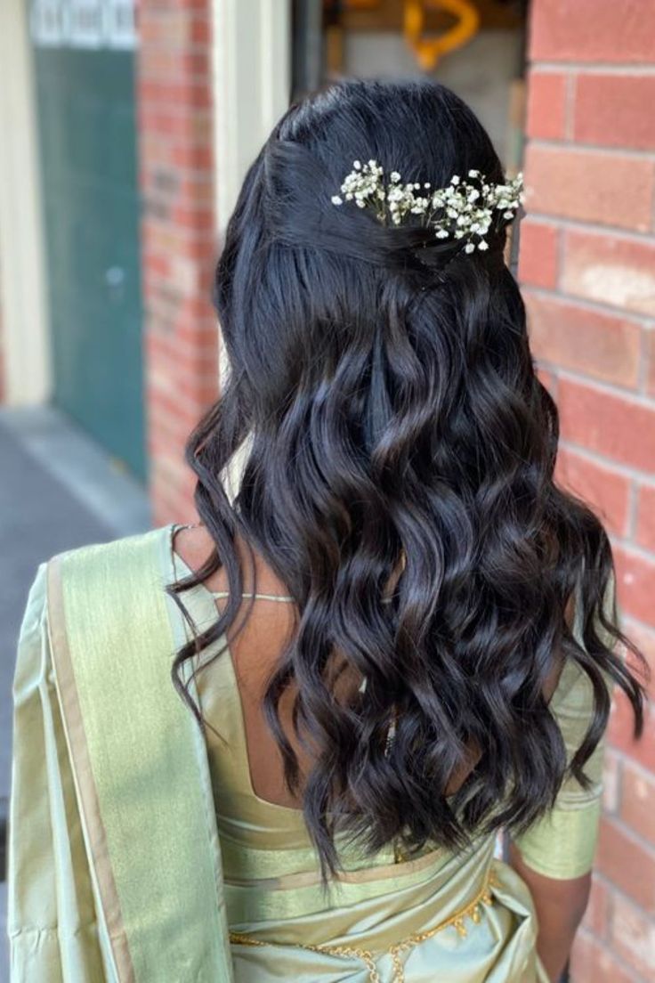 the back of a woman's head with long hair and flowers in her hair